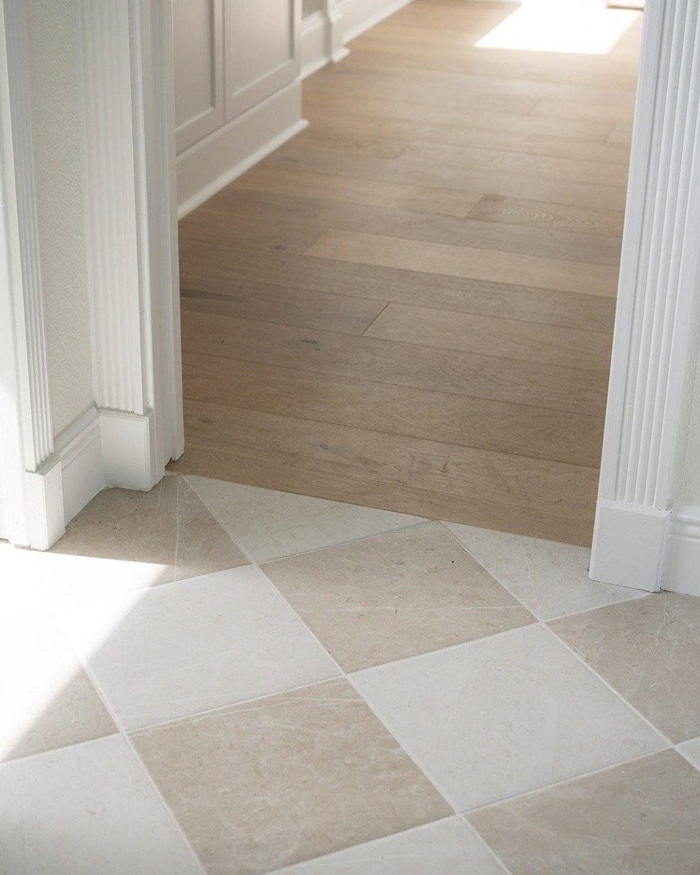 LVP That Looks Like Real Wood: 6 Ideas to Pull It Off 6 Light wood-look flooring planks meeting cream and beige checkered tiles at a white doorway entrance.