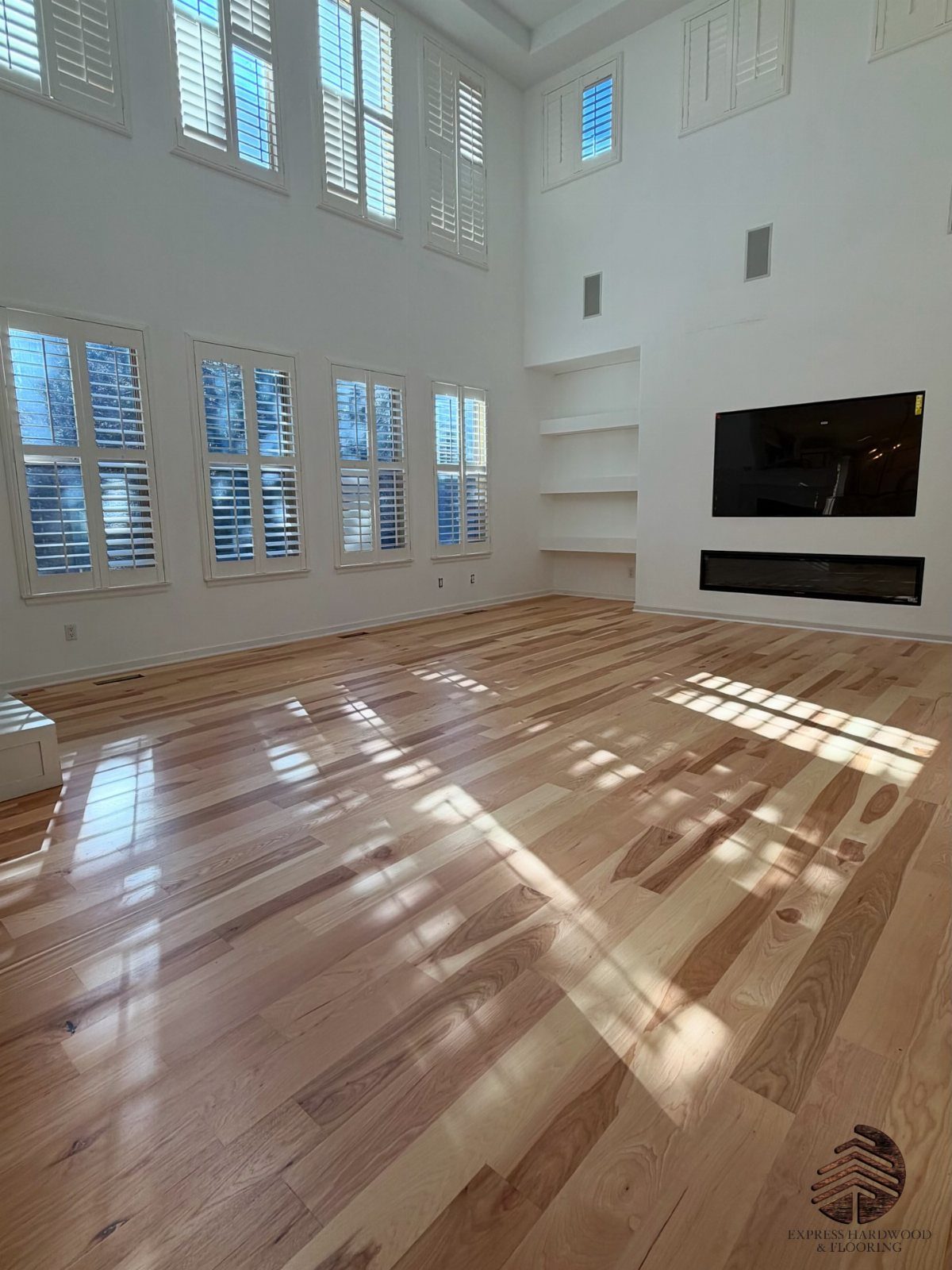 Medium Hardwood Floors: 5 Rooms That Get the Tone Right 3 Polished medium-toned hardwood floors reflecting sunlight in a bright, modern room with white walls.
