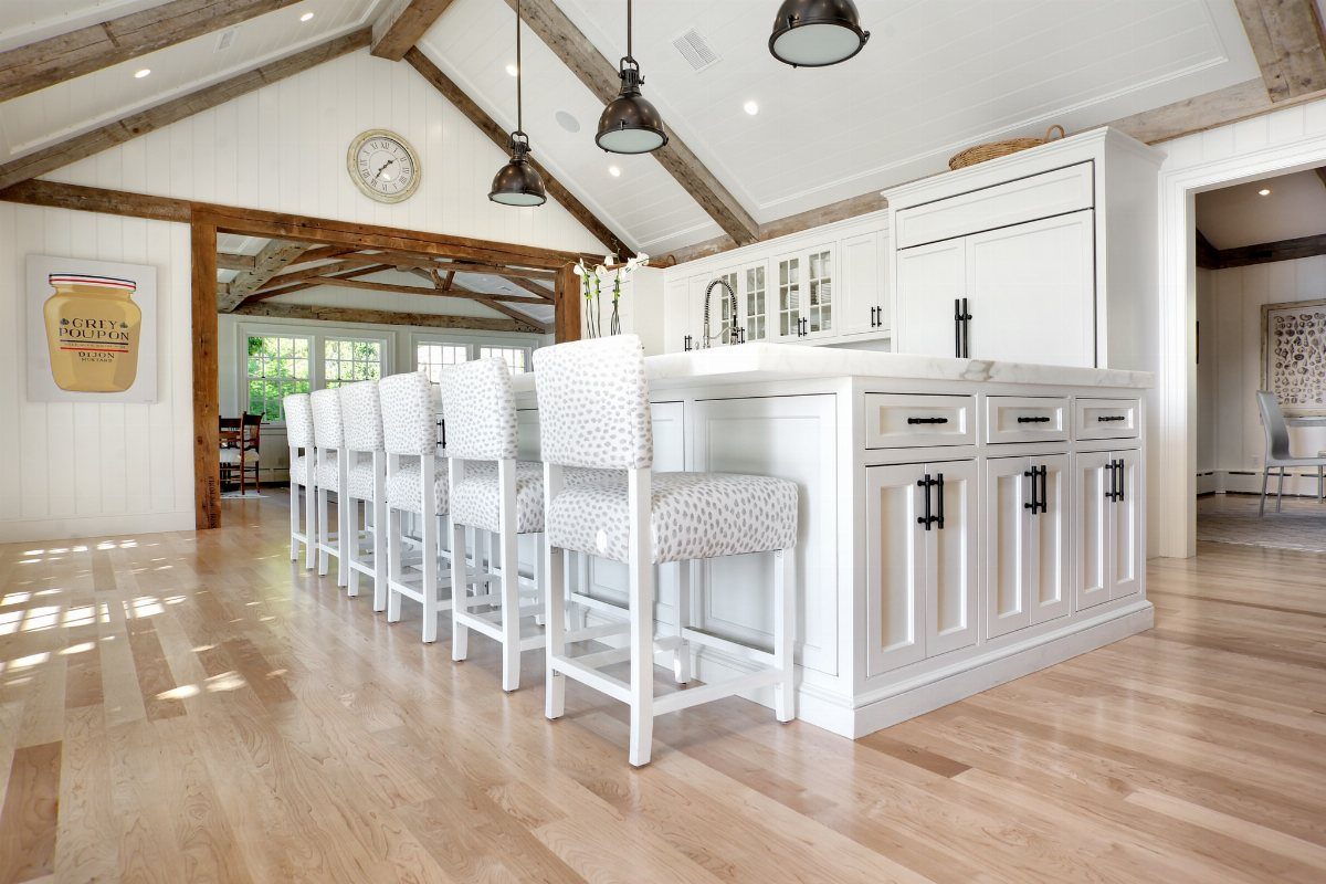 Medium Hardwood Floors: 5 Rooms That Get the Tone Right 1 Light maple hardwood floors in a bright, modern kitchen with a white island and bar stools.