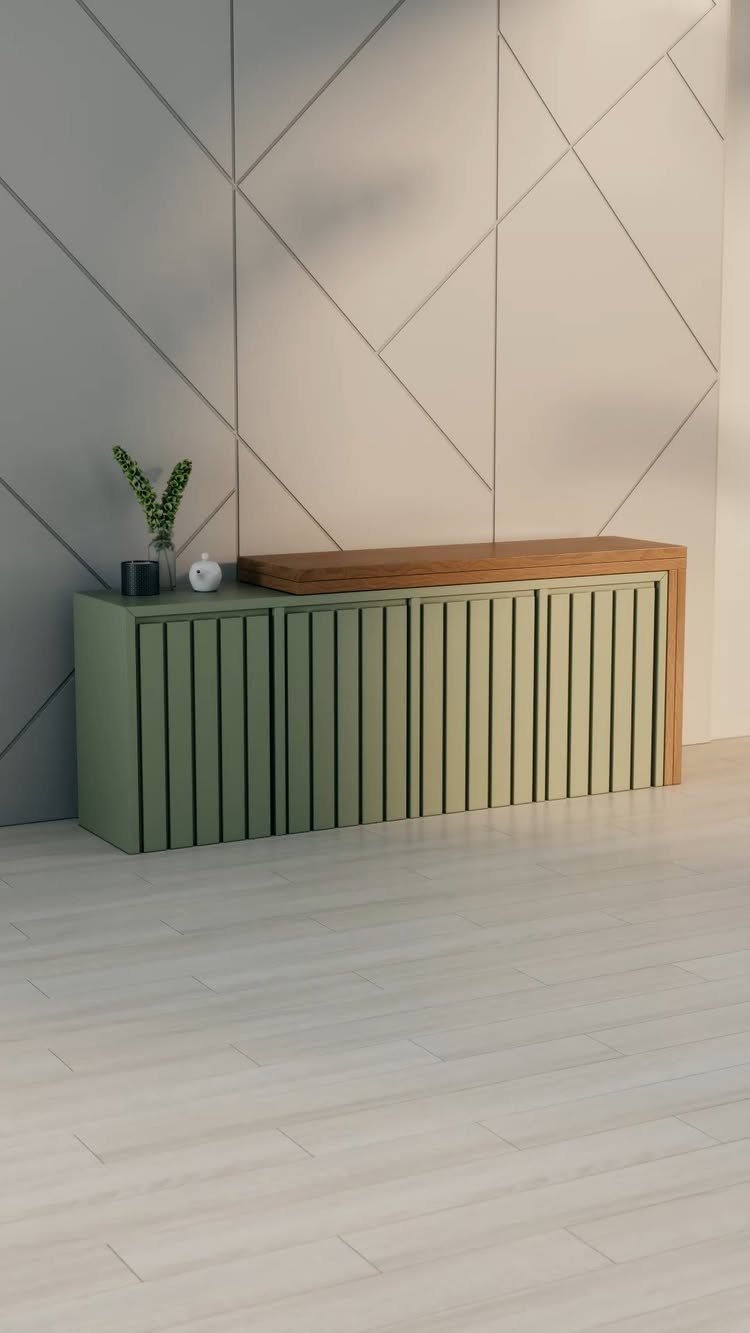 A sage green slatted sideboard with a wooden top against a geometric patterned grey wall.