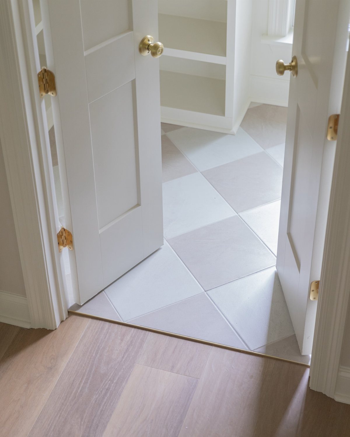 10 Modern Farmhouse Flooring Ideas for Every Room 8 Checkerboard pattern floor tiles visible through open white double doors in a bright room.