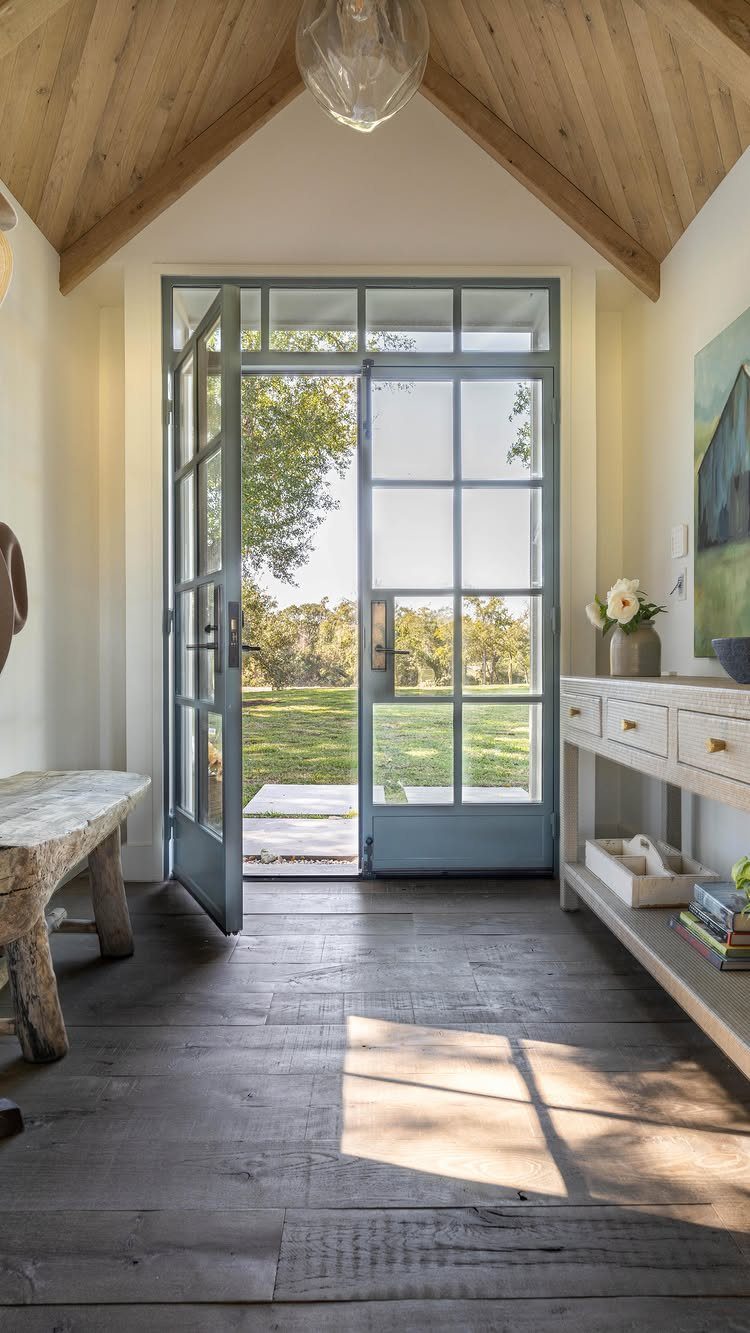 10 Modern Farmhouse Flooring Ideas for Every Room 1 Wide grey wood planks flooring in a bright entryway with open blue French doors.
