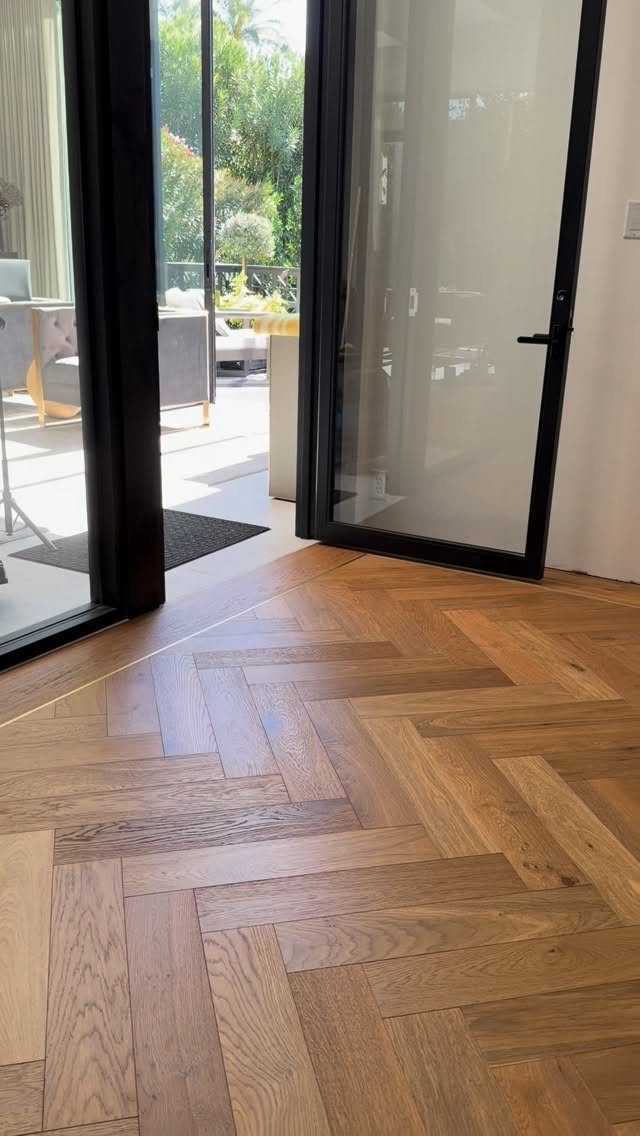 Parquet Floor Pattern: 8 Historic Layouts That Still Define Interiors 2 Light brown wooden parquet floor with a herringbone pattern near a glass door.