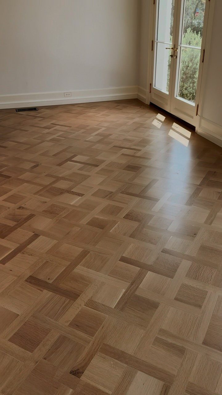 Parquet Floor Pattern: 8 Historic Layouts That Still Define Interiors 6 Wooden parquet floor with a basket weave pattern in a bright room with white walls.