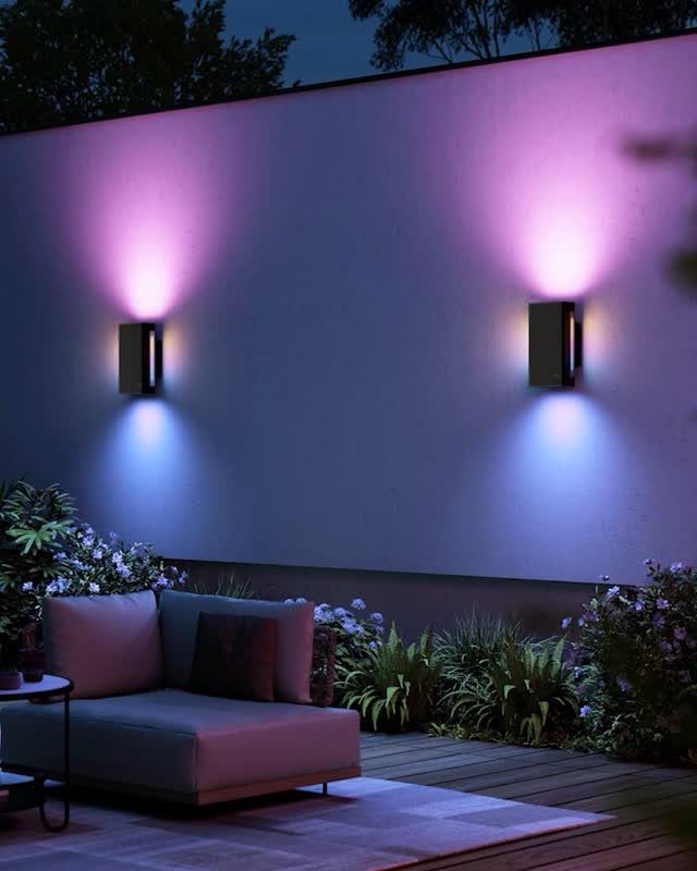 25 Patio Lights Ideas, From String Lights to Step Lighting 10 Modern black wall sconces casting purple and blue light on a patio wall.