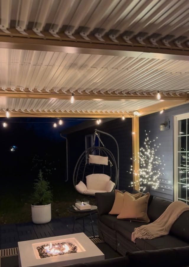 25 Patio Lights Ideas, From String Lights to Step Lighting 1 Outdoor patio with warm string lights under a roof and a modern fire pit.
