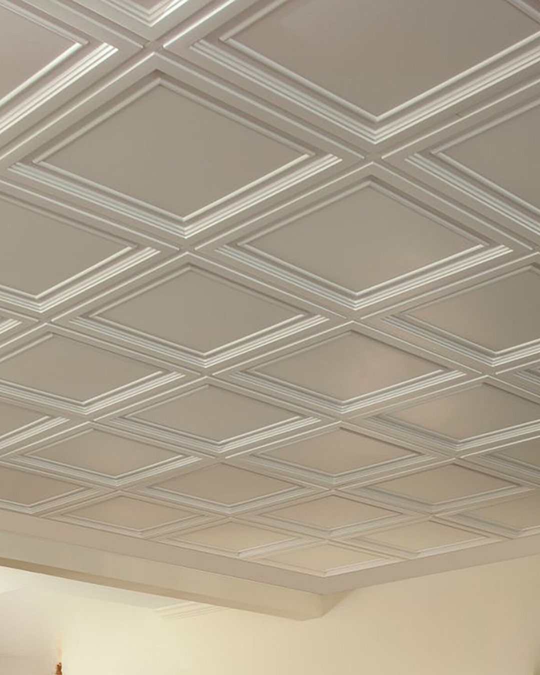 White coffered ceiling with a geometric pattern of recessed diamond-shaped panels and decorative molding.