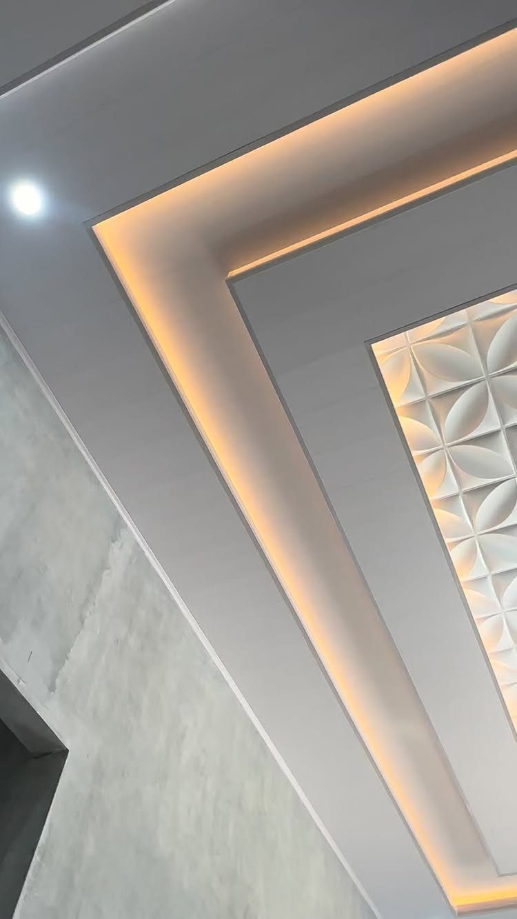 Modern false ceiling with white 3D geometric textured panels and warm cove lighting.