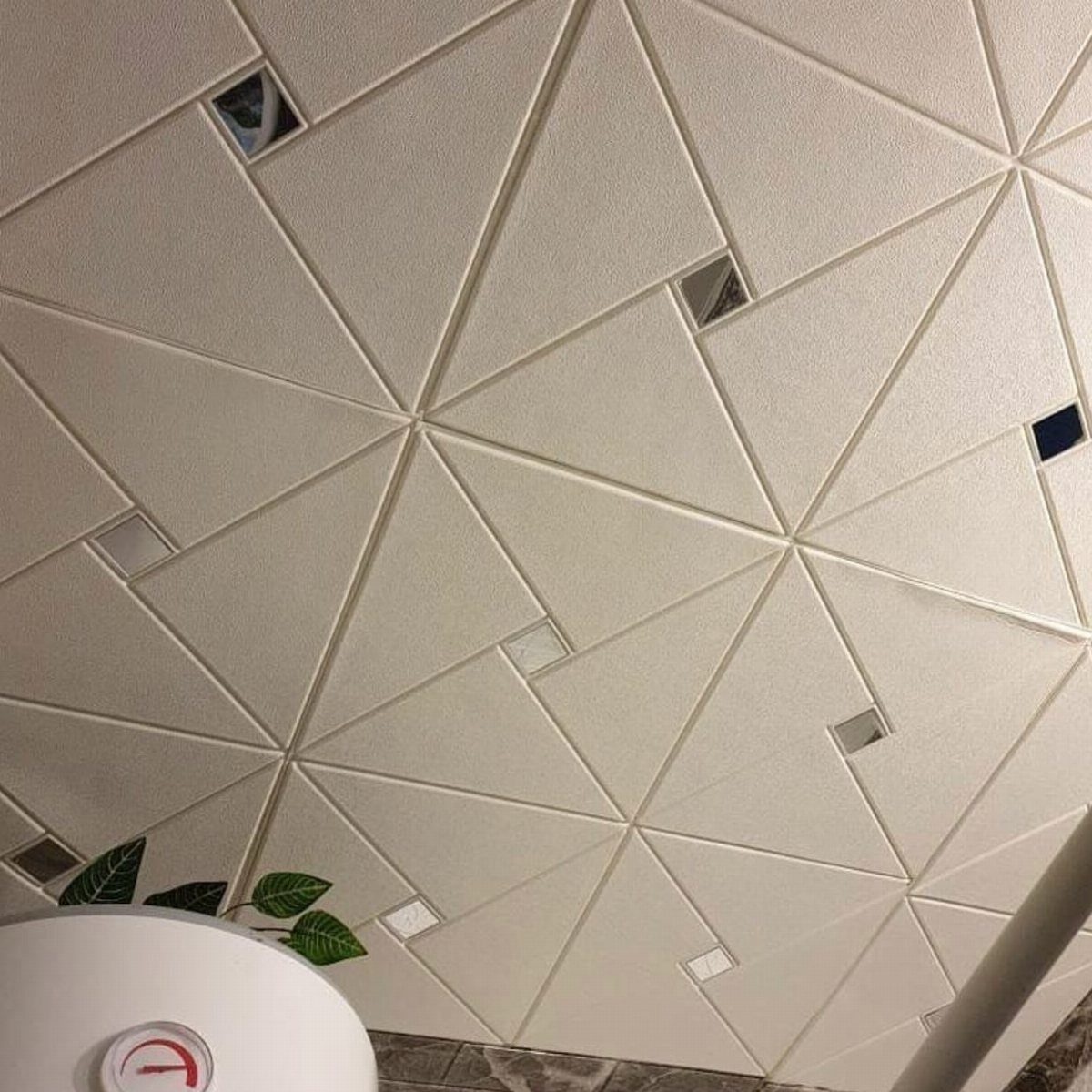 White geometric triangular panels with small mirrored square accents forming a textured pattern.