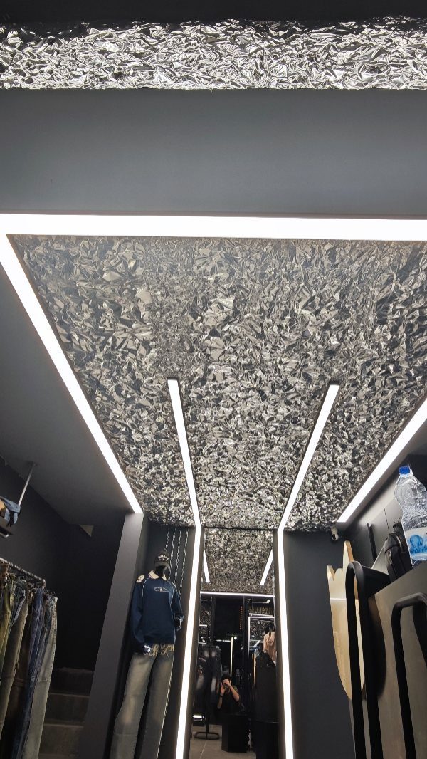 Silver metallic textured PVC ceiling with bright white LED strip lighting in a modern interior.