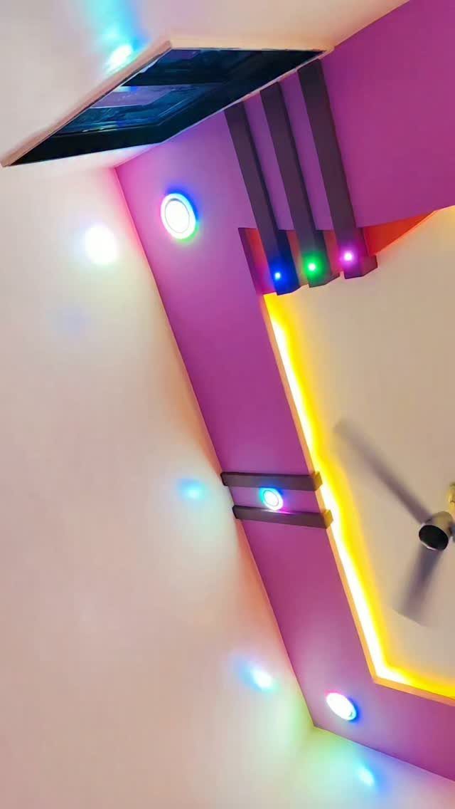 Modern POP ceiling with purple panels, colorful LED lights, and yellow cove lighting.