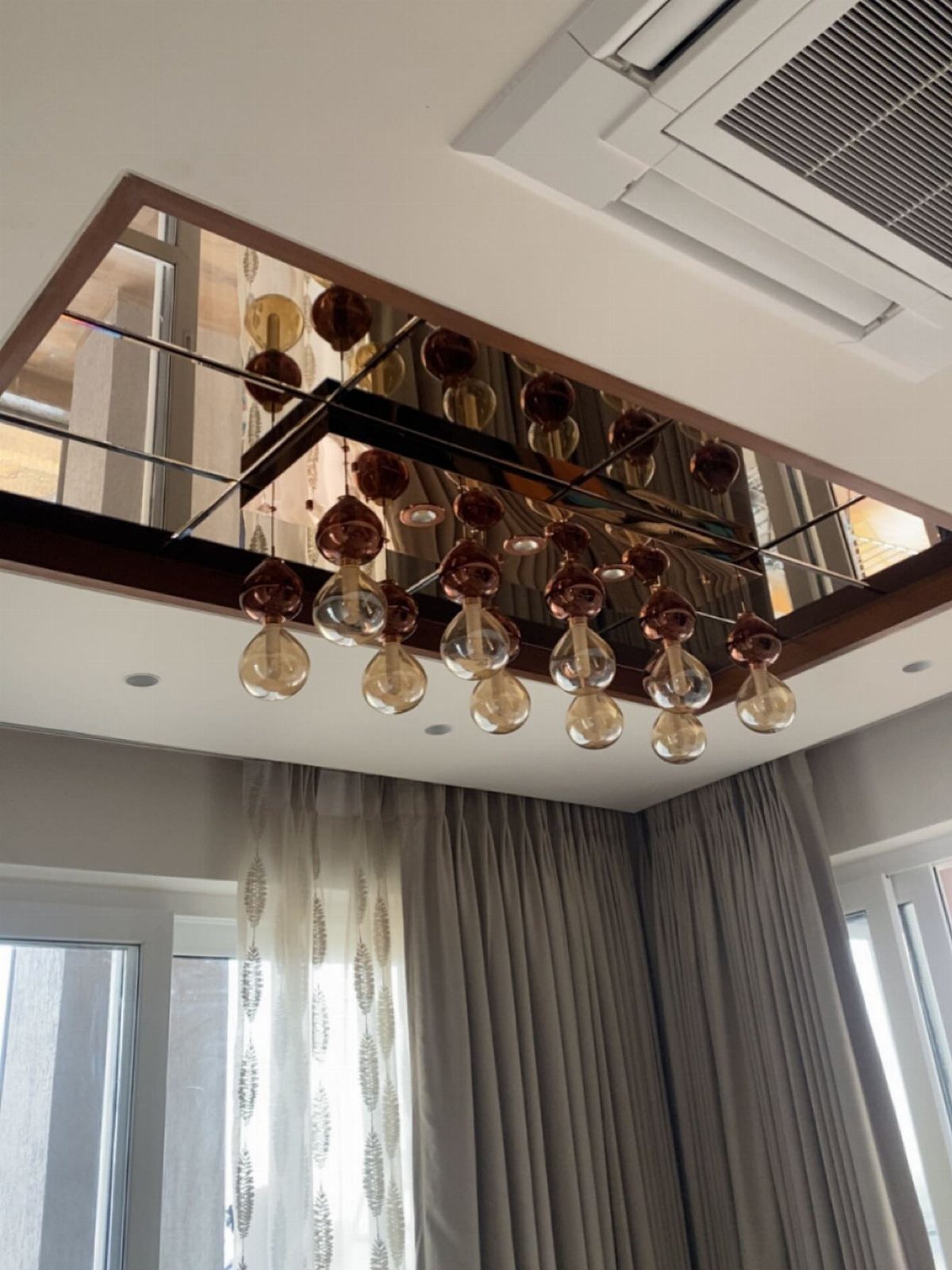 Mirrored glass ceiling insert with a dark wood frame and amber glass globe chandelier.