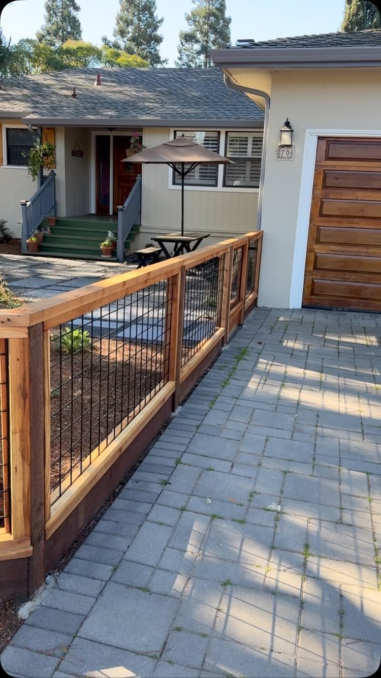 Natural wood fence with wire mesh panels along a stone paver walkway.