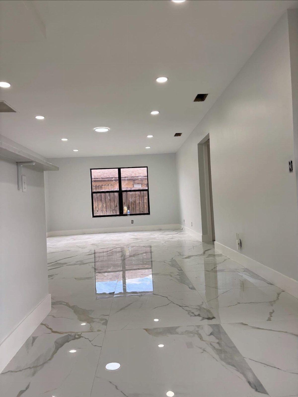 Types of Flooring: 10 Ideas from Hardwood to Rubber 5 White marble-patterned glazed ceramic tile flooring in a bright, empty room with reflective surfaces.