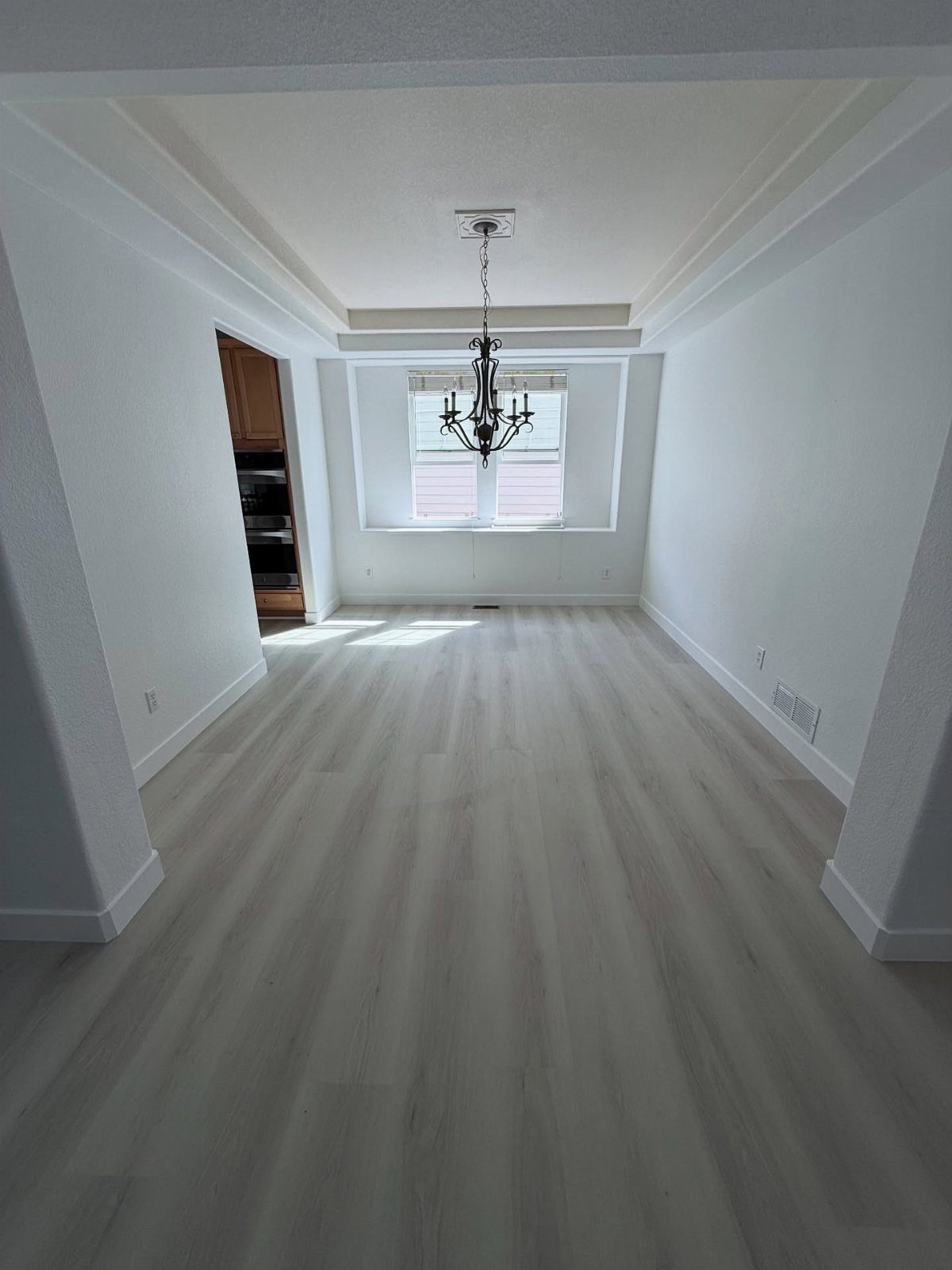 Types of Flooring: 10 Ideas from Hardwood to Rubber 9 Light-colored wide-plank wood flooring in an empty room with white walls and a chandelier.