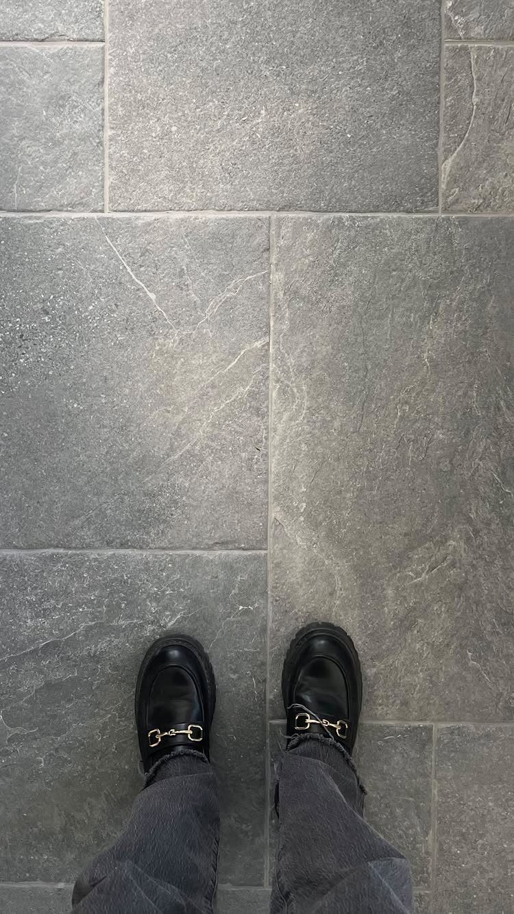 Types of Flooring: 10 Ideas from Hardwood to Rubber 10 Grey stone floor tiles with natural veining and a person's feet in black loafers.