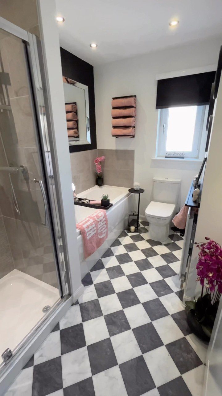 9 Vinyl Floor Colors for Every Room in 2026 9 Black and white checkered tile flooring in a modern white bathroom with a bathtub and toilet.
