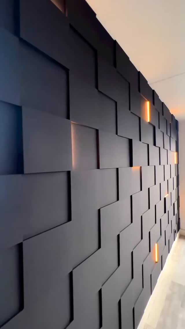9 Wall Paneling Accent Wall Ideas for Every Room 8 Geometric dark grey wall panels with integrated warm orange light strips in a modern room.