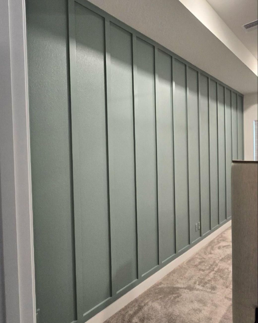 9 Wall Paneling Accent Wall Ideas for Every Room 1 Sage green board and batten wall paneling installed in a carpeted hallway.