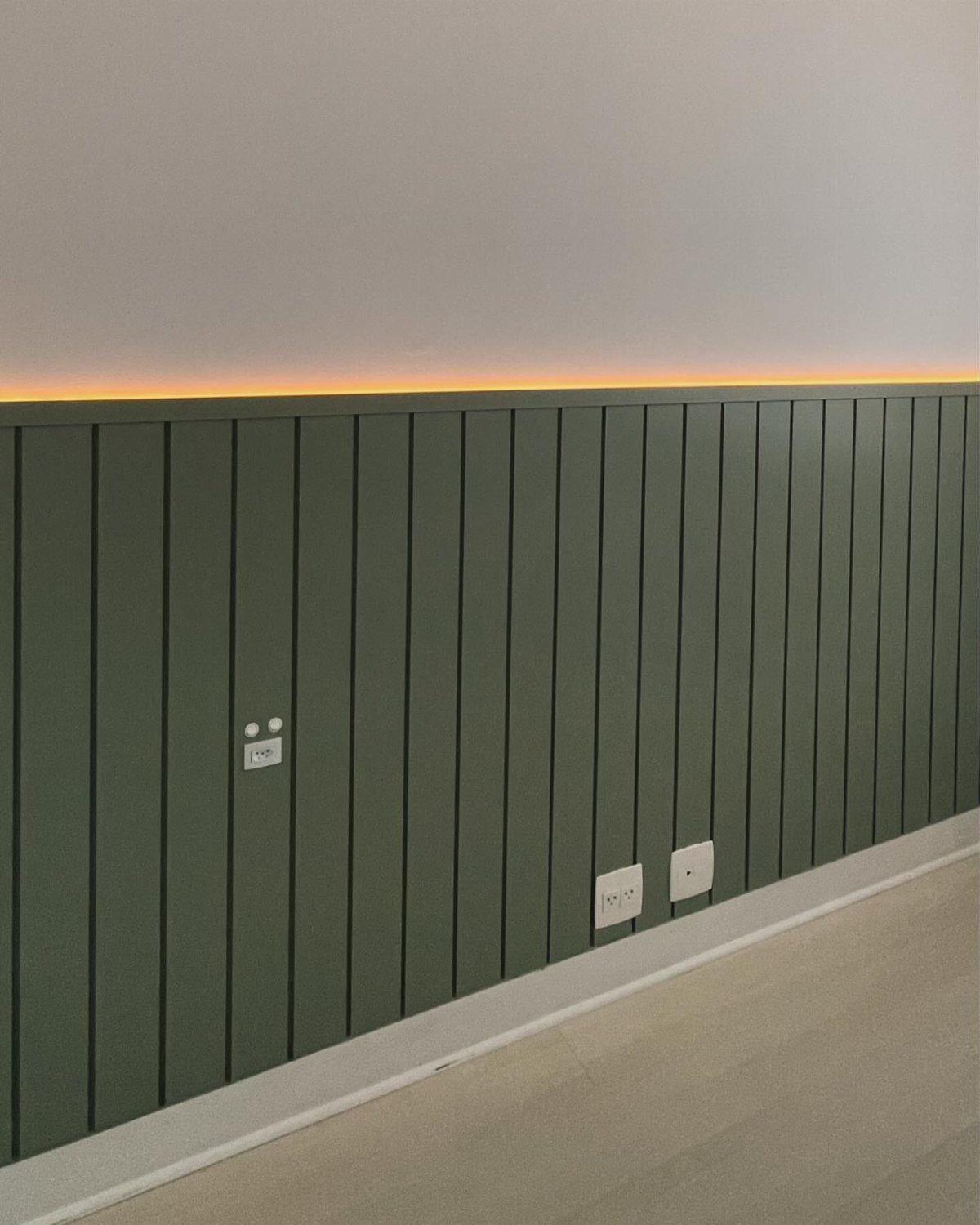 9 Wall Paneling Accent Wall Ideas for Every Room 4 Sage green vertical shiplap wall paneling with warm LED lighting along the top edge.