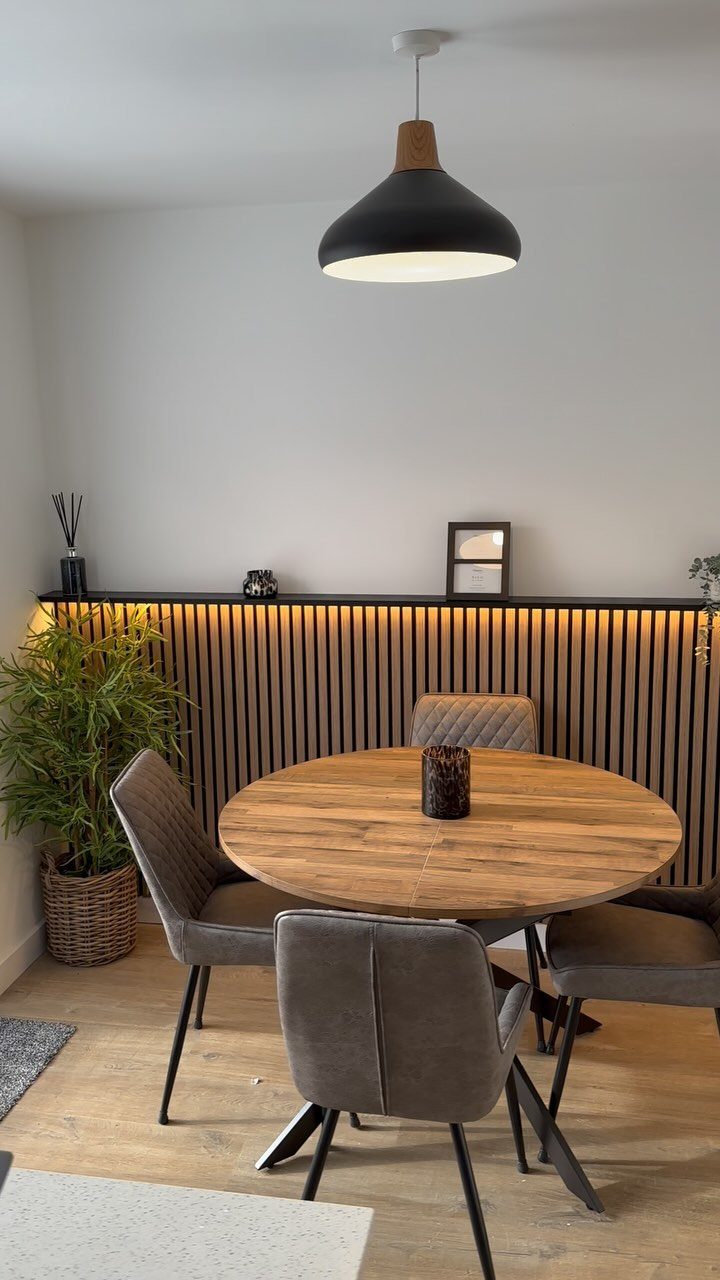 Vertical black wooden slats with warm LED lighting installed on a dining room wall.