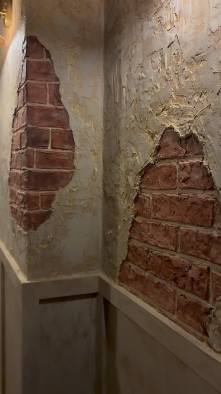 Wall Texture Design: 12 Ideas for Every Room 7 Distressed plaster wall revealing red brick texture in two large irregular patches.
