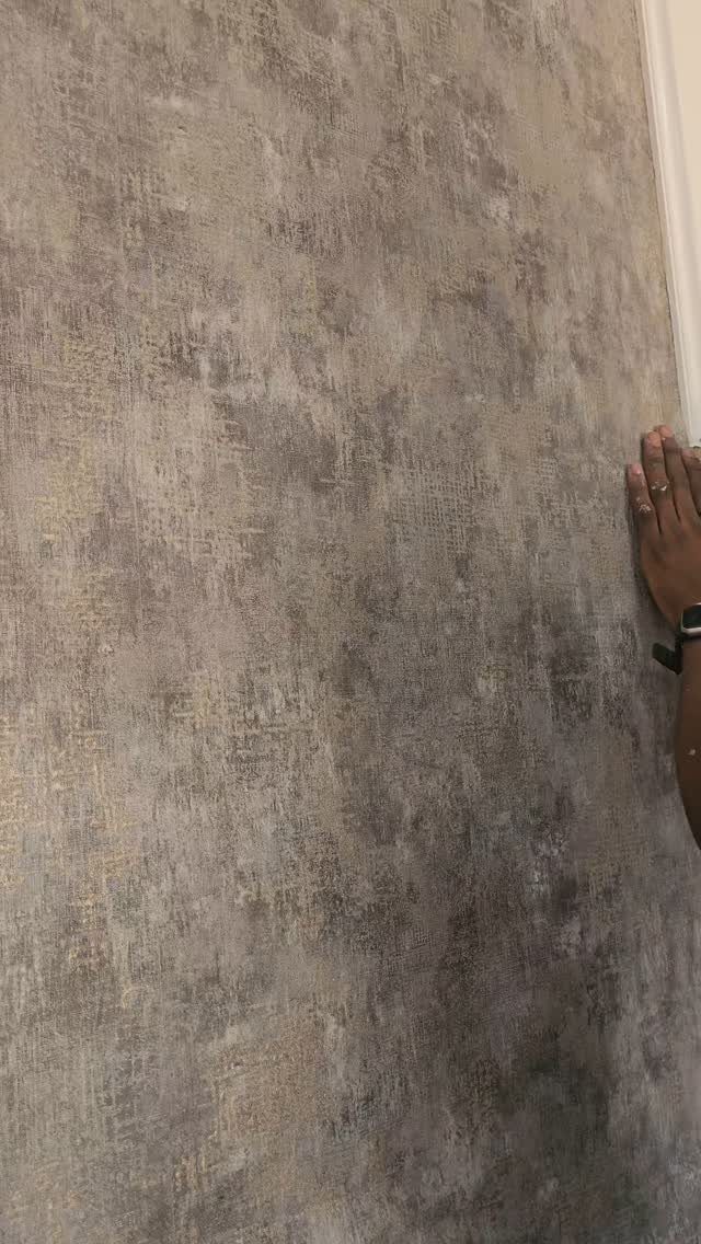 Wall Texture Design: 12 Ideas for Every Room 10 Textured wall with mottled grey and beige tones being touched by a hand.