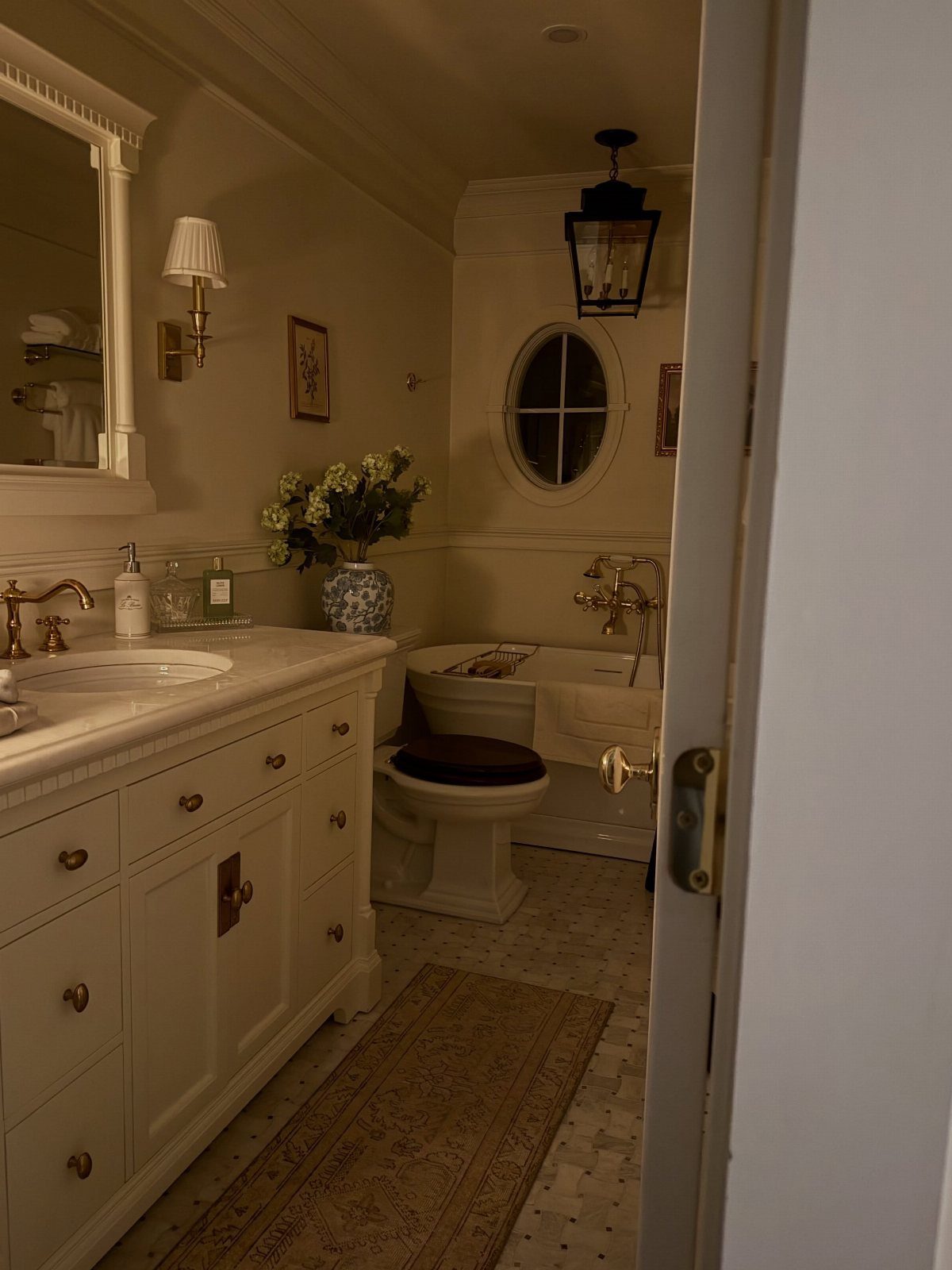 White bathroom with a vanity, clawfoot tub, and beige runner rug on the floor.