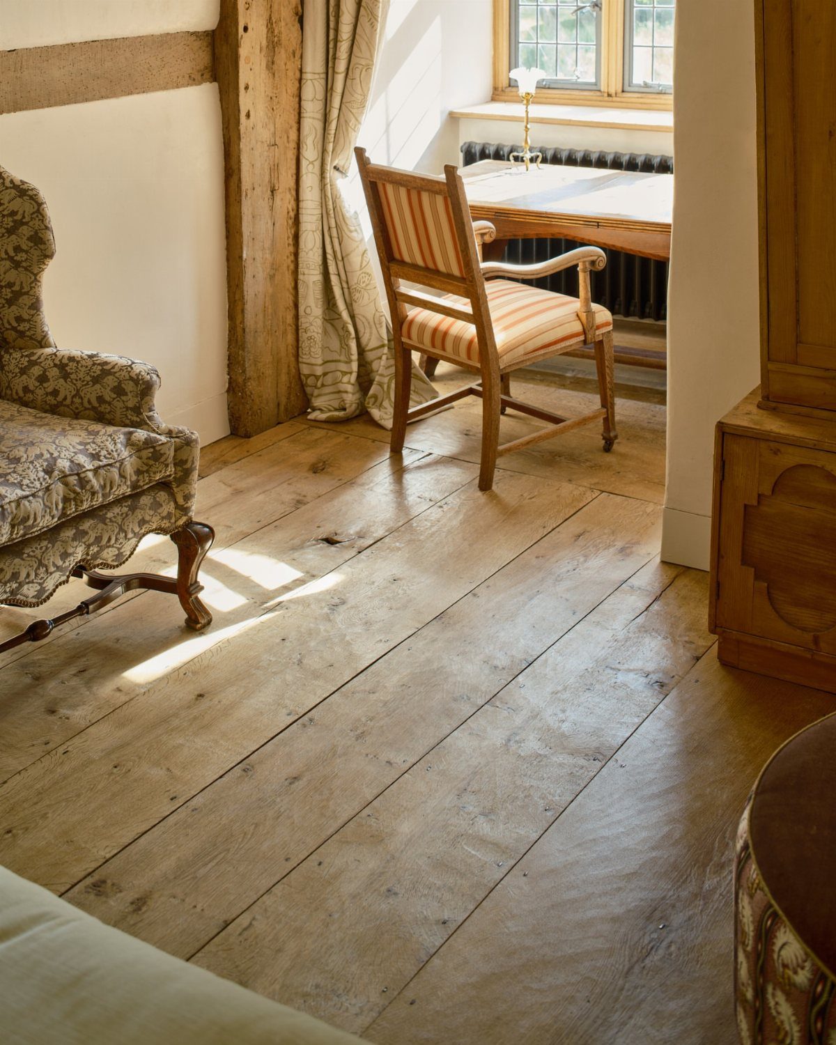 Wide solid oak floorboards with natural grain in a bright, rustic living room setting.